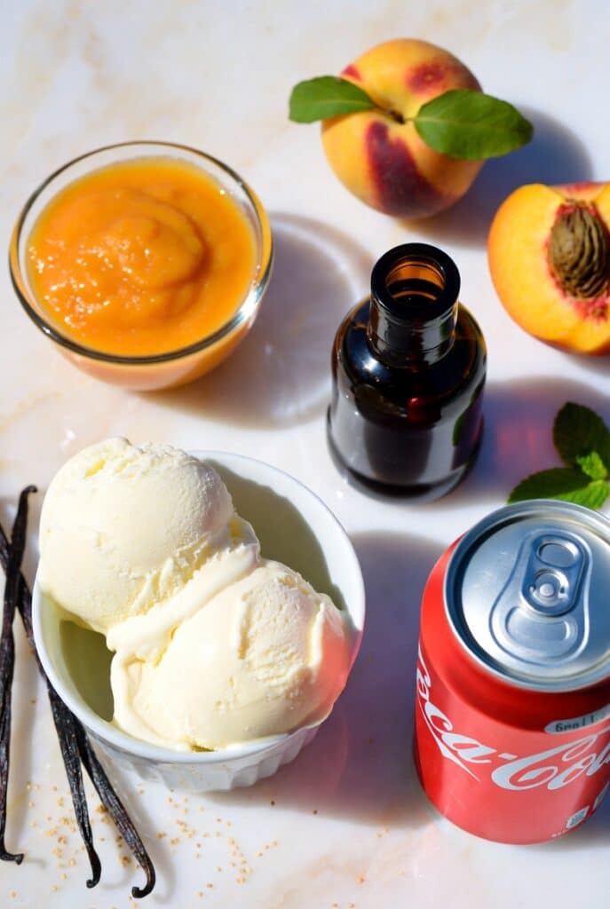 Peach Vanilla Coke Float: The Irresistible Summer Drink Recipe 6 Flat lay of fresh ingredients needed to make a Peach Vanilla Coke Float including vanilla ice cream, peaches, puree, and Coca-Cola