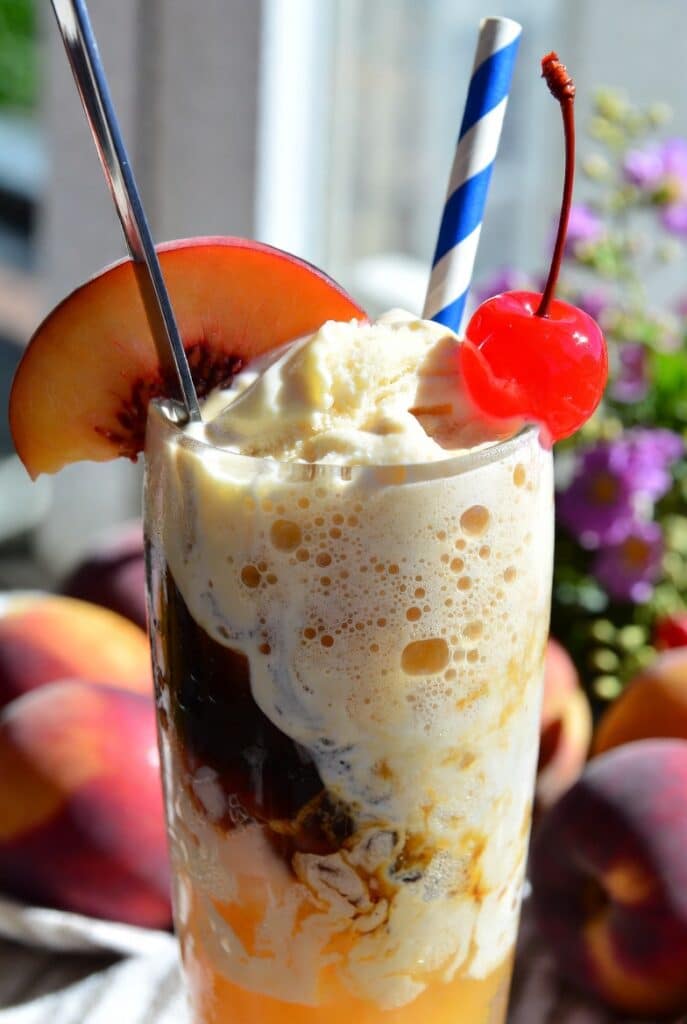 Peach Vanilla Coke Float: The Irresistible Summer Drink Recipe 7 Close-up of a finished Peach Vanilla Coke Float in a tall glass with spoon, straw, peach slice, and cherry garnish
