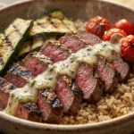 Grilled Steak Bowl with Creamy Sauce topped with fresh herbs and zucchini.